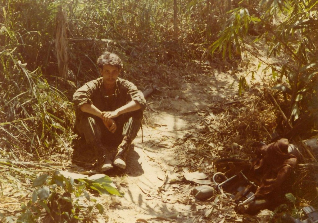 Medic sitting on well-used trail. Song Be, Vietnam 1970