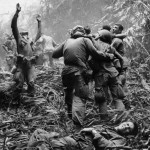 In a 1968 Associated Press photo from Vietnam by Art Greenspon, a soldier guides an unseen medevac helicopter to a jungle clearing where wounded comrades wait.