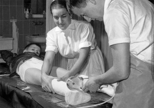 A doctor removes a cast from a young patient as a nurse looks on. Circa 1967. Photo: FEIN GmbH. Stuugart, Germany.